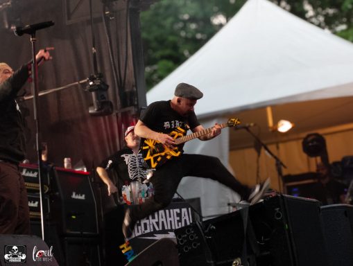 Musician jumping while playing an electric guitar on stage during a live performance.