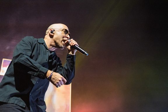 +LIVE+ - Centre Videotron A singer performing on stage with a microphone, wearing sunglasses and a black shirt.