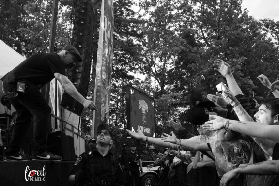 A performer leans over a crowd, with fans reaching out in excitement.