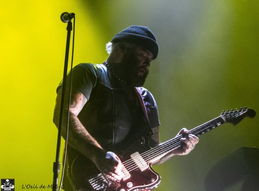 Musician playing guitar on stage with dramatic yellow lighting.