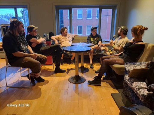 A group of six people sitting around a table in a cozy room.