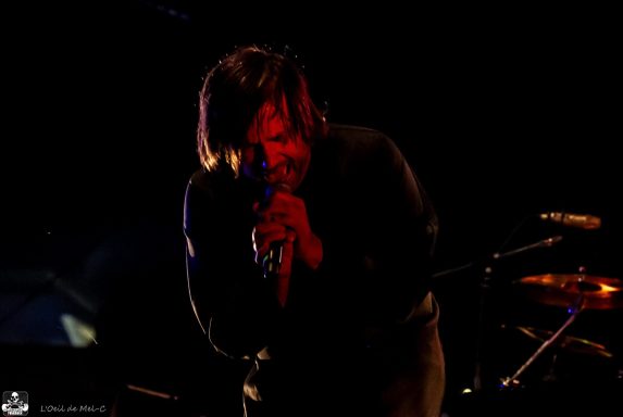 A singer passionately performing on stage with dramatic lighting.