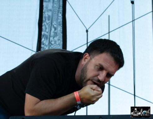 A musician performing passionately on stage, leaning forward with intense focus.