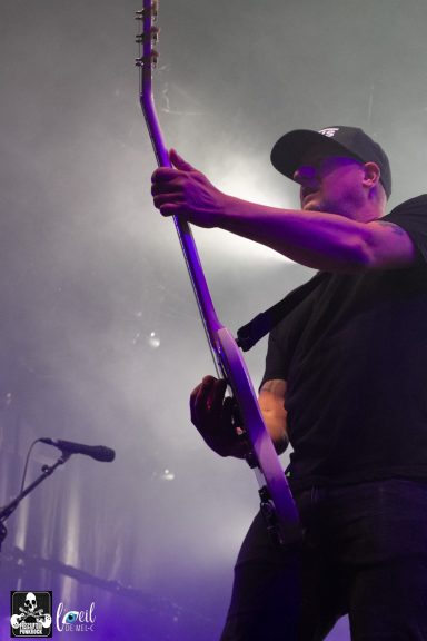 A musician playing an electric guitar on stage with dramatic lighting.