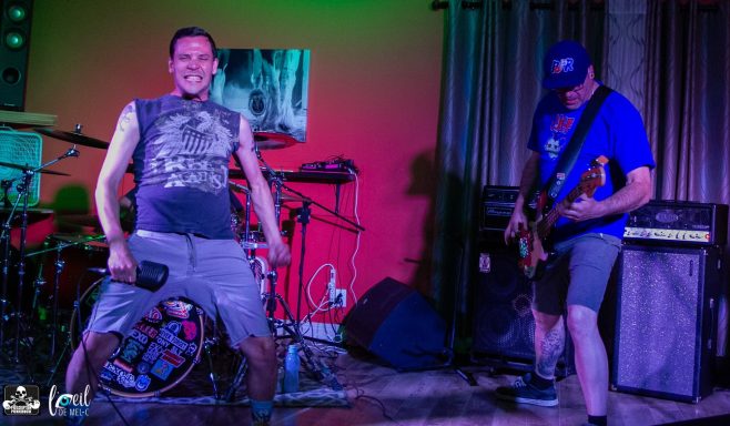 Two musicians performing on stage, one singing and the other playing guitar.