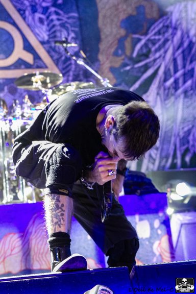 A musician performing on stage, bent forward with microphone in hand.