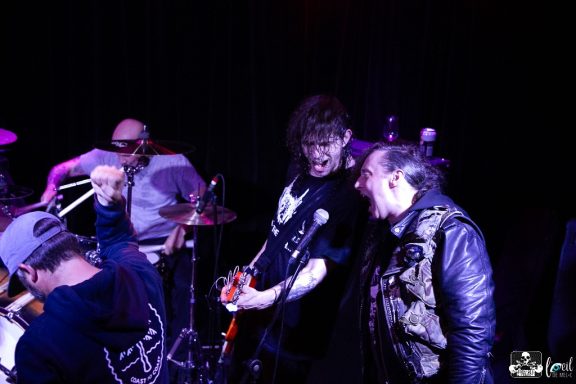 Musicians performing on stage with instruments and energetic expressions.