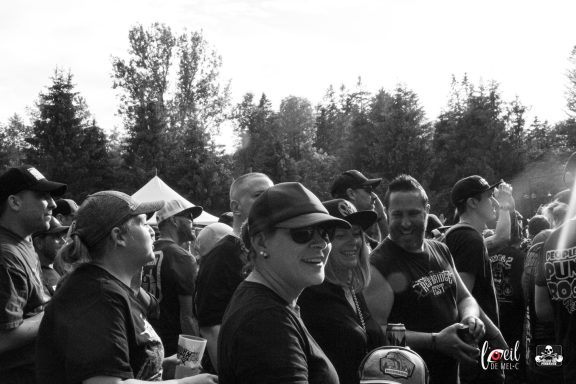 A crowd of people in a park, wearing caps and enjoying an outdoor event.