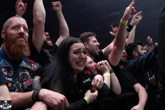 Crowd at a concert, showing excitement with raised arms and varied expressions.