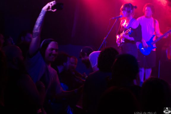 Band performing live on stage, with audience enthusiastically dancing and enjoying the music.