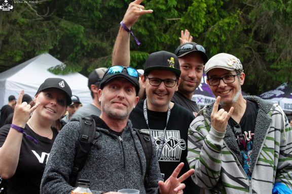 A group of five people posing with hand signs at an outdoor event.