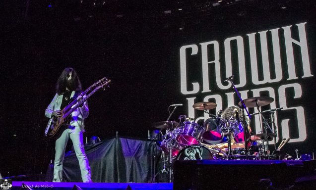 Musician performing on stage with a large "CROWN LANDS" backdrop.