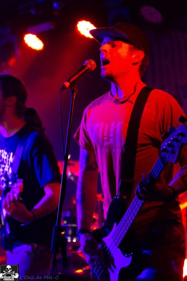 Two musicians perform on stage, one singing and the other playing an electric guitar.