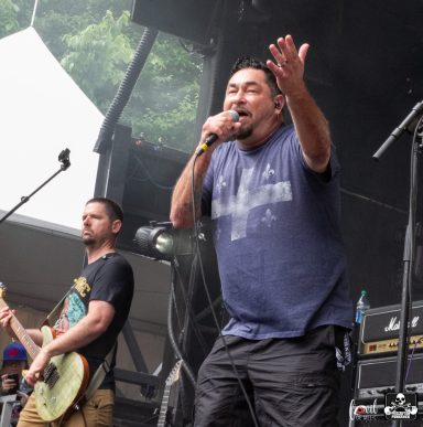 Two male musicians performing on stage, with one singing into a microphone.