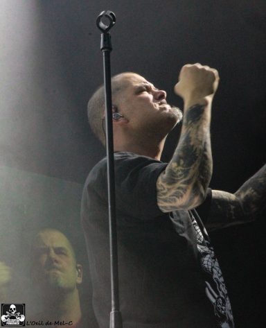 A singer with tattoos passionately performing on stage.