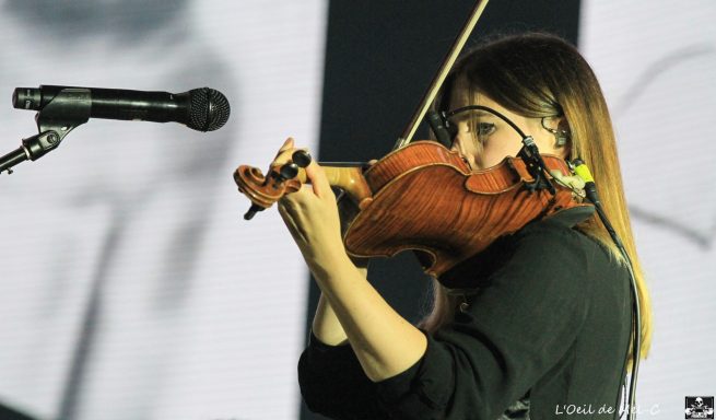 Violinist performing passionately on stage with a microphone nearby.