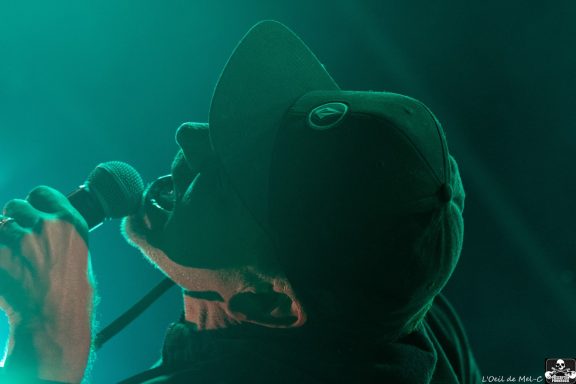 Person singing passionately into a microphone under dramatic lighting.