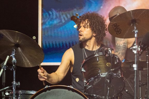 +LIVE+ - Centre Videotron Drummer playing energetically on stage, with colorful background lights.