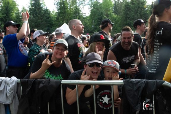 Crowd of enthusiastic concertgoers, showing excitement and making hand signs.