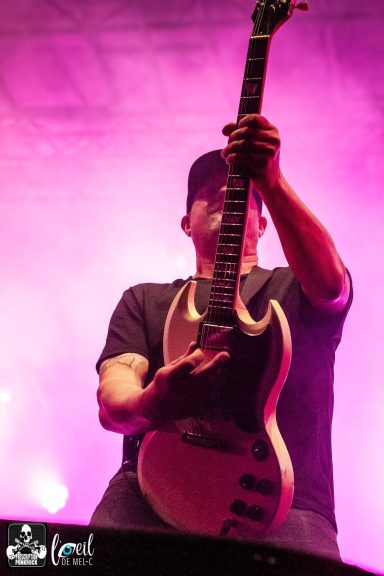 A musician playing an electric guitar under colorful stage lights.