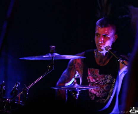 Drummer performing on stage, illuminated by colorful stage lights.