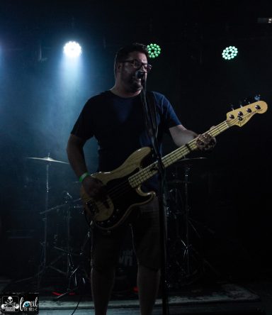 From Old Town - L'Anti-Bar & Spectacles A musician playing bass guitar on stage, performing under dramatic lighting.
