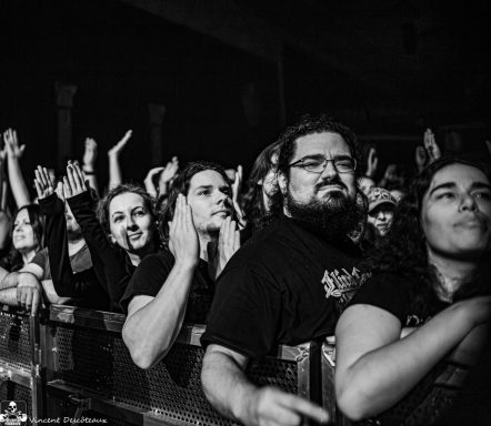Crowd at a concert, with people cheering and enjoying the performance.